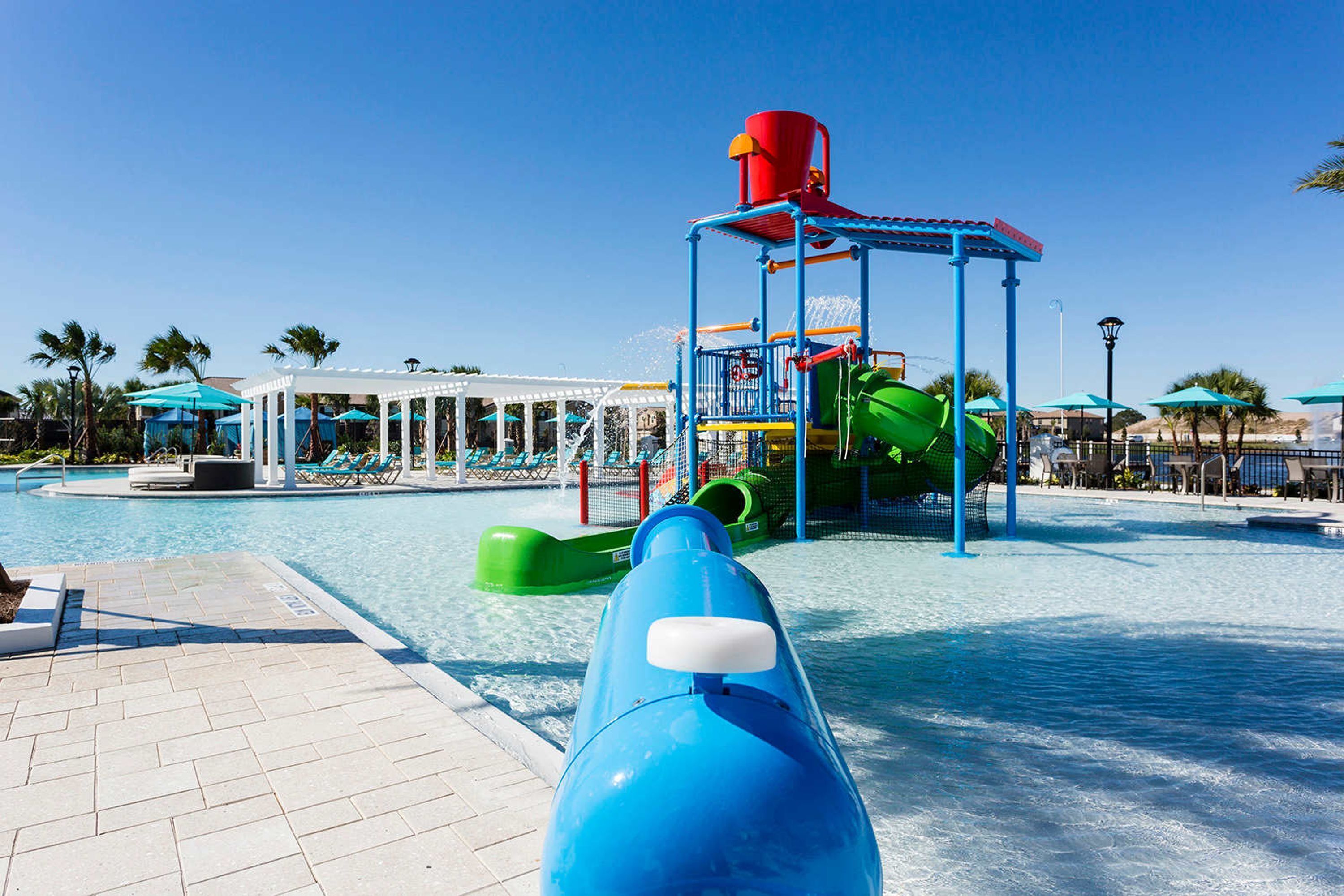 Een waterpark met een blauwe glijbaan, een groene glijbaan en een rode watertoren.