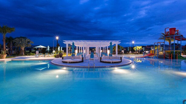 Una piscina con un pabellón central, sillas de descanso y un tobogán de agua.