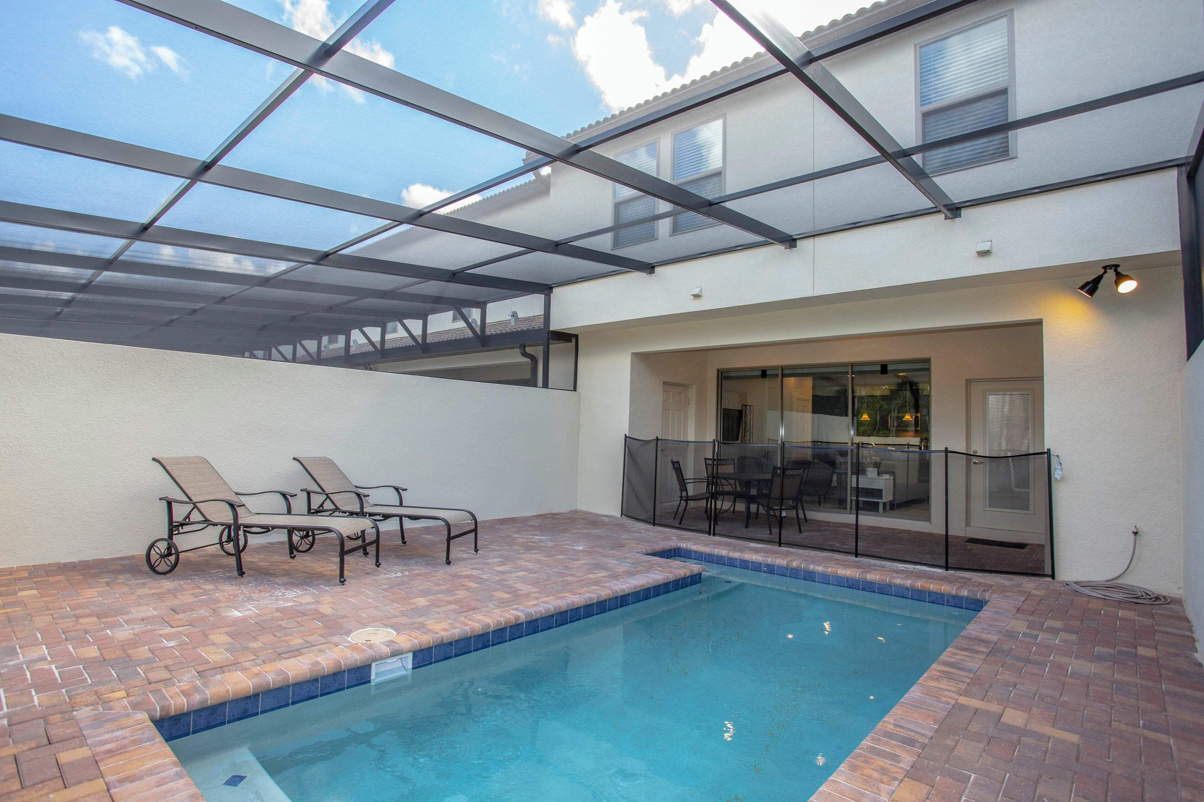 Ein Hallenbad mit Glasdach, eine Terrassenfläche mit Liegestühlen sowie eine überdachte Terrasse mit Tisch und Stühlen.
