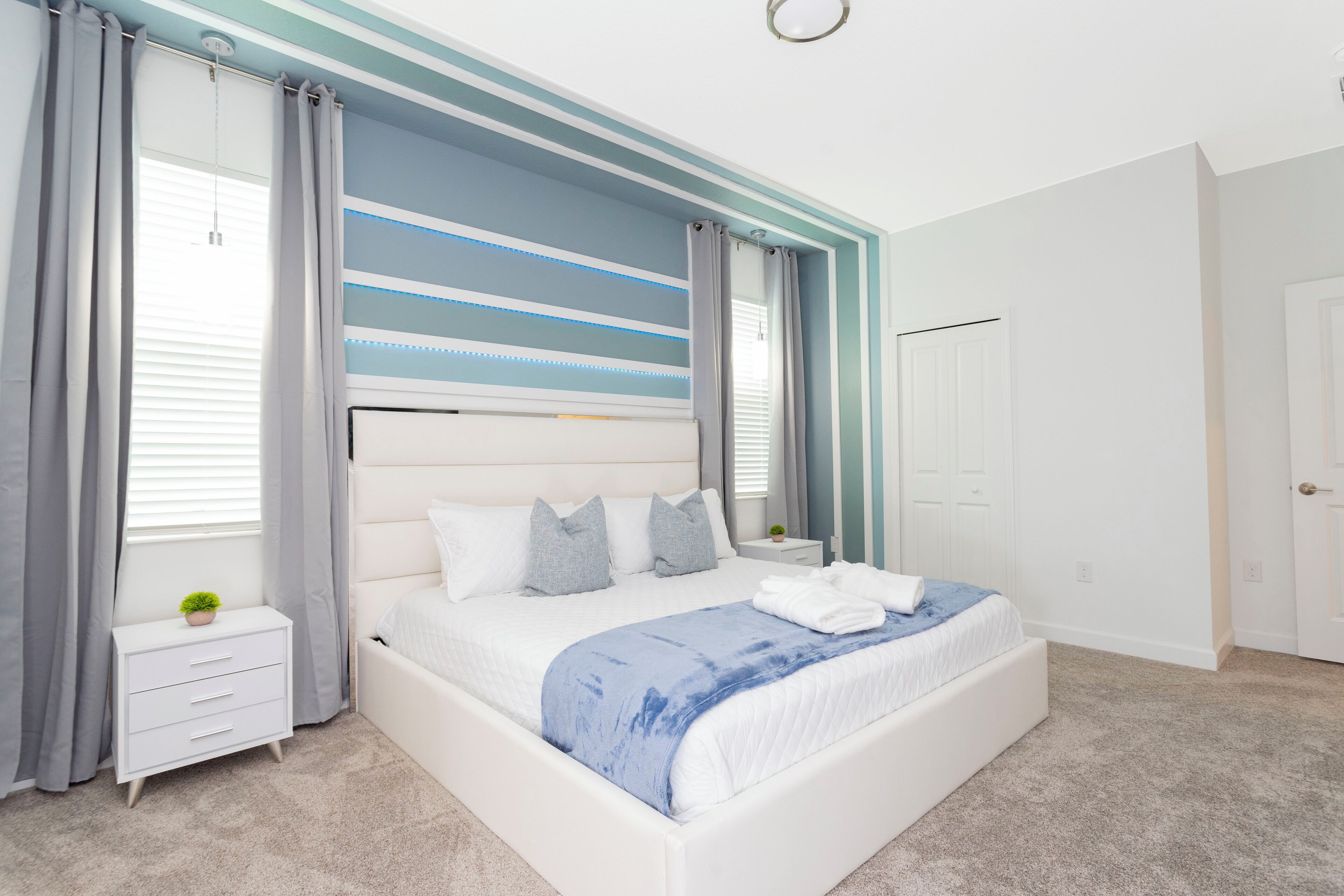 Een moderne slaapkamer met een groot bed, een nachtkastje en een raam met gordijnen.