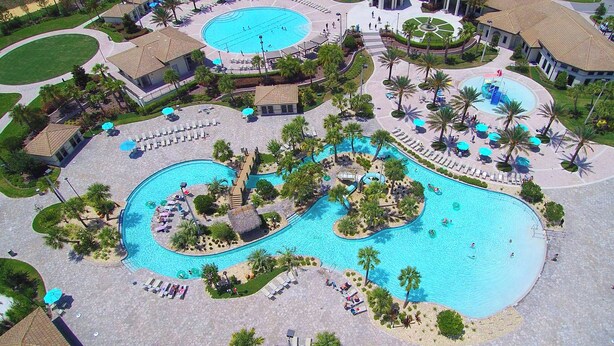 A resort with multiple swimming pools, sun loungers, and palm trees. - Joyful 8Bd Single Family w Pool Champions Gate 9262 (Davenport)