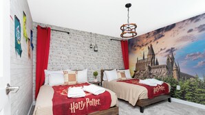 A room with two beds, each with a Harry Potter themed bedspread, a brick wall, and a large mural of Hogwarts castle. - Joyful 8Bd Single Family w Pool Champions Gate 9262 (Davenport)
