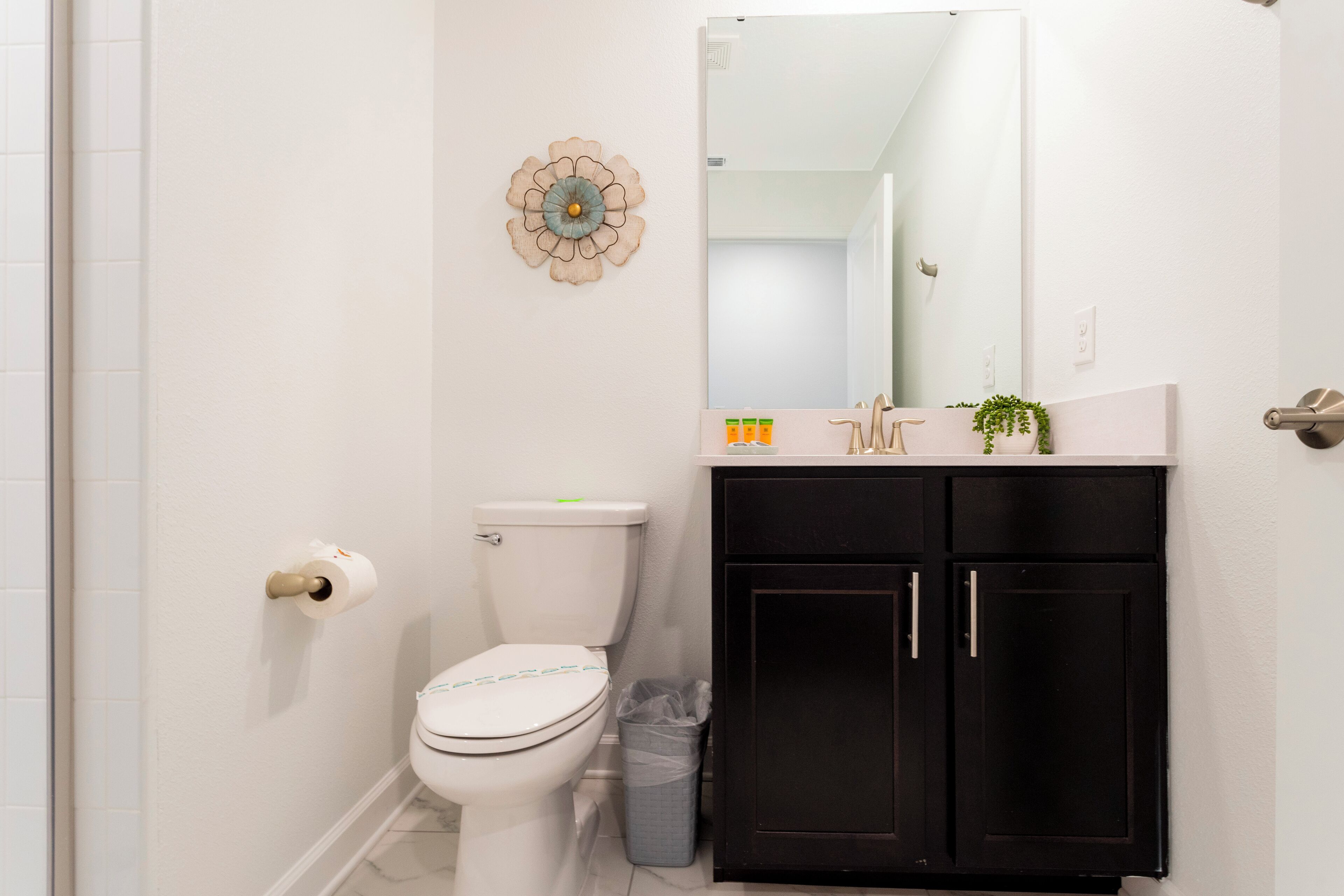 Un baño con inodoro, lavabo, espejo y cubo de basura.