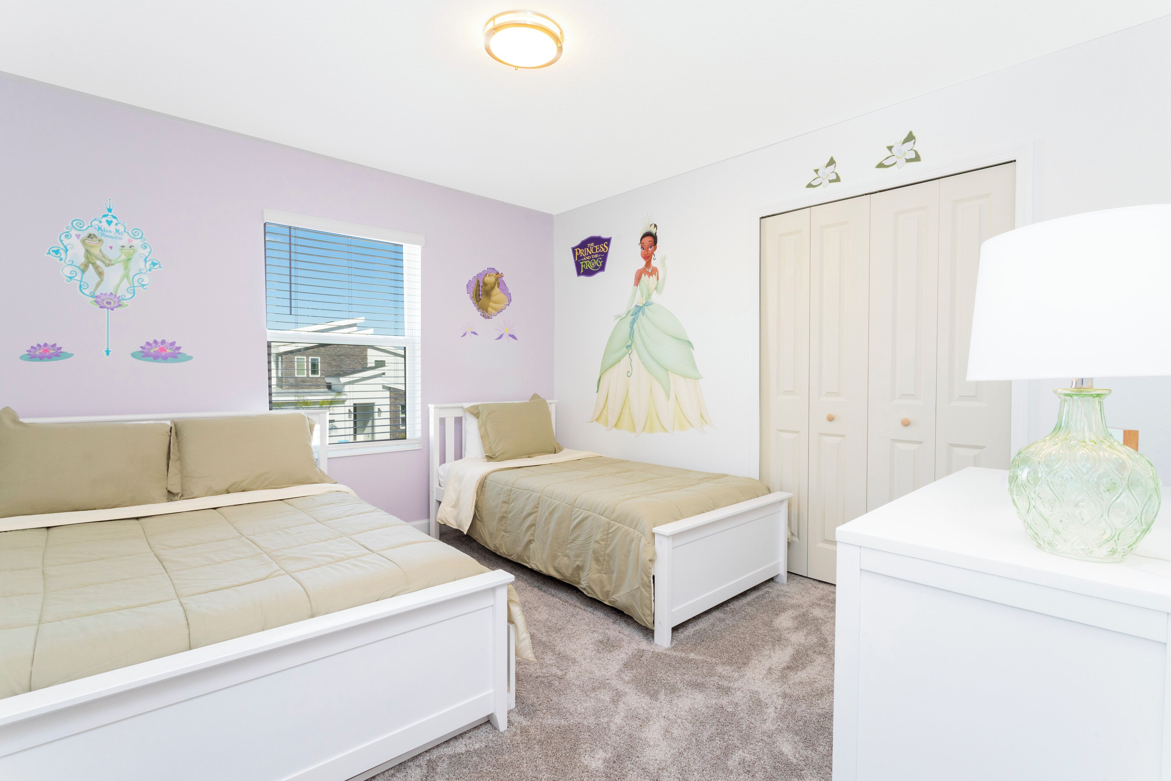 A bedroom with two beds, a window, a door, and wall decorations including a princess poster.