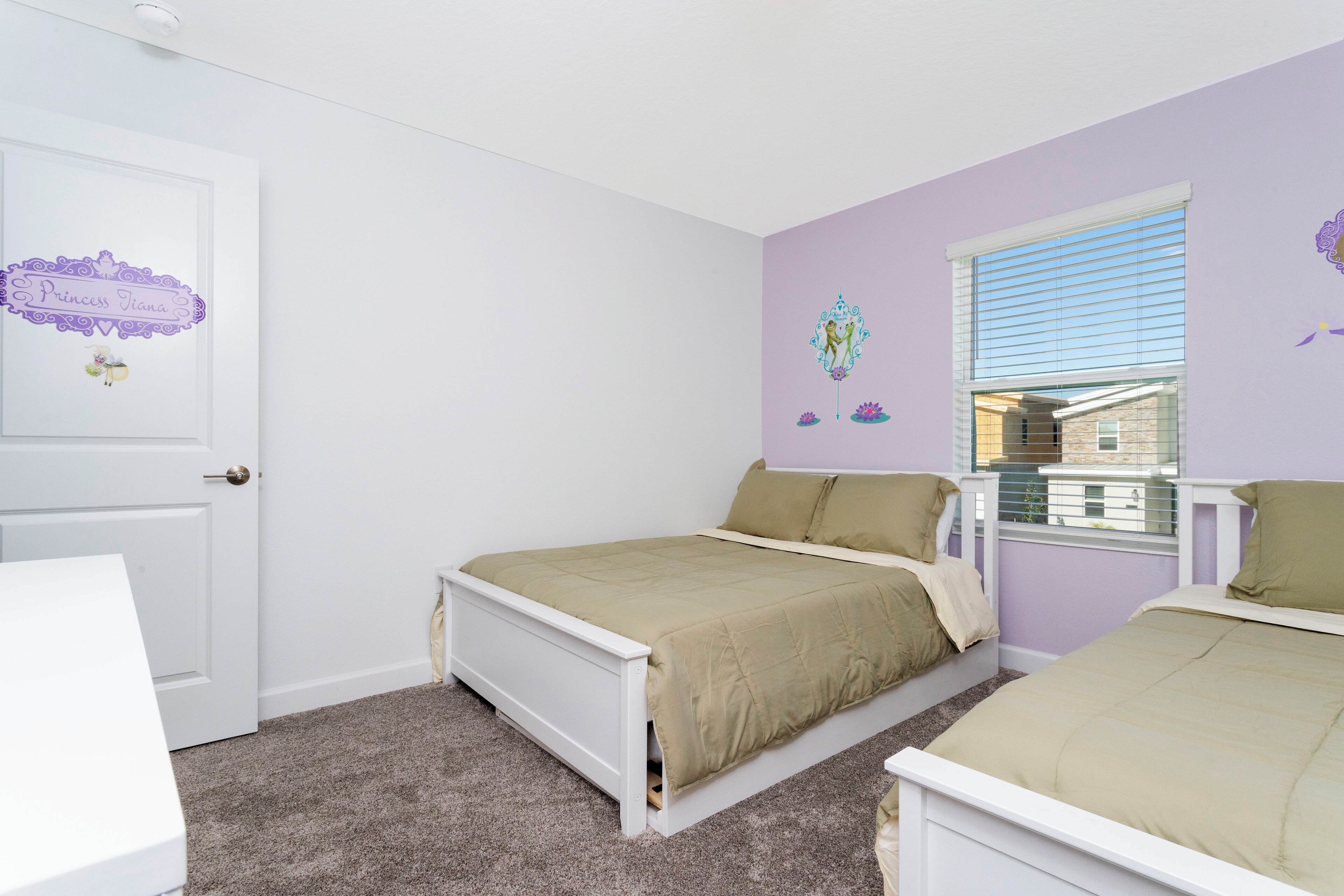 A bedroom with two single beds, a white door, and a window with blinds.
