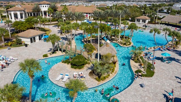 A large outdoor swimming pool with multiple lanes, surrounded by palm trees and lounge chairs. - Fabulous 5 Bedrooms Close to Disney at Champions Gate Resort 8988 (Kissimmee)
