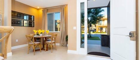 Una habitación con una mesa de comedor, sillas, una ventana con cortinas y una puerta que da al exterior.