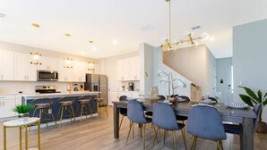 Une cuisine moderne avec des meubles blancs, un îlot central et des tabourets de bar.