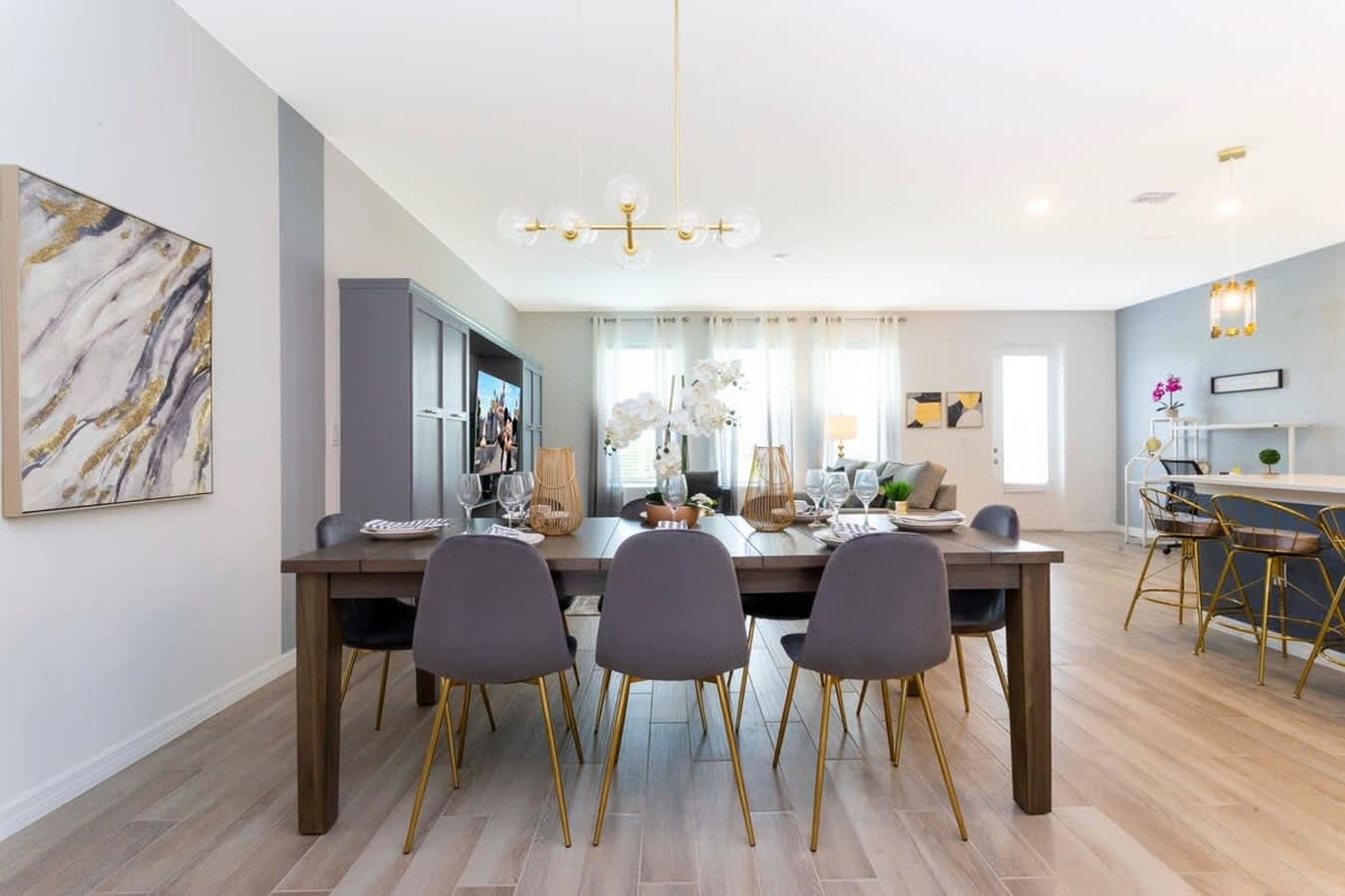 A modern dining area with a wooden table, four chairs, and a chandelier.