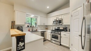 Une cuisine moderne avec des armoires blanches, des appareils en acier inoxydable et un îlot central en bois.