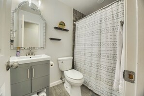 A bathroom with a white sink, a toilet, and a shower curtain. - Home Away from Home in South Austin (Austin)