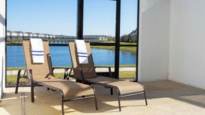 Deux fauteuils de jardin avec des serviettes, une vue sur un lac et un bâtiment en arrière-plan.