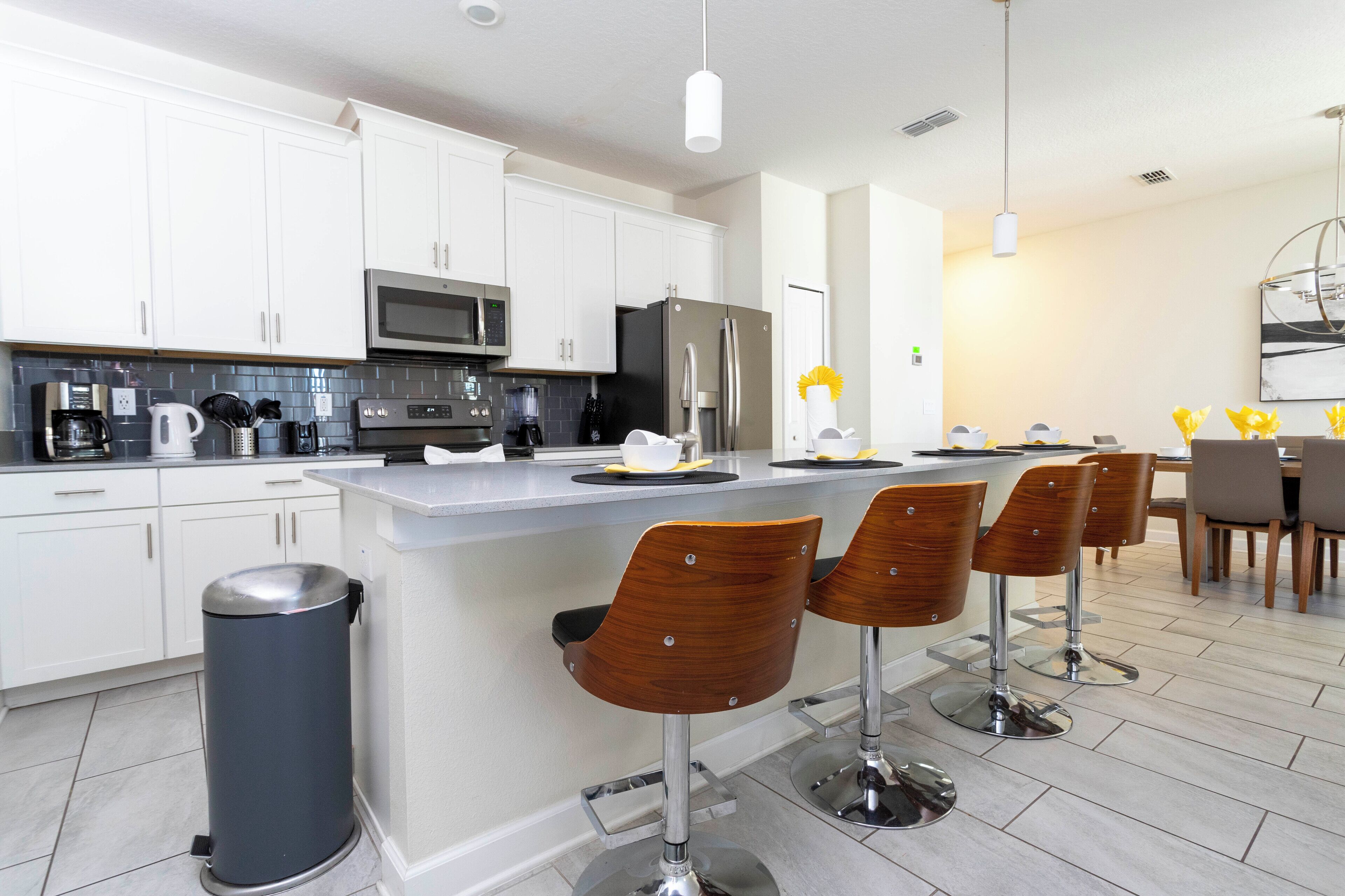 A modern kitchen with white cabinets, stainless steel appliances, and a central island with bar stools.