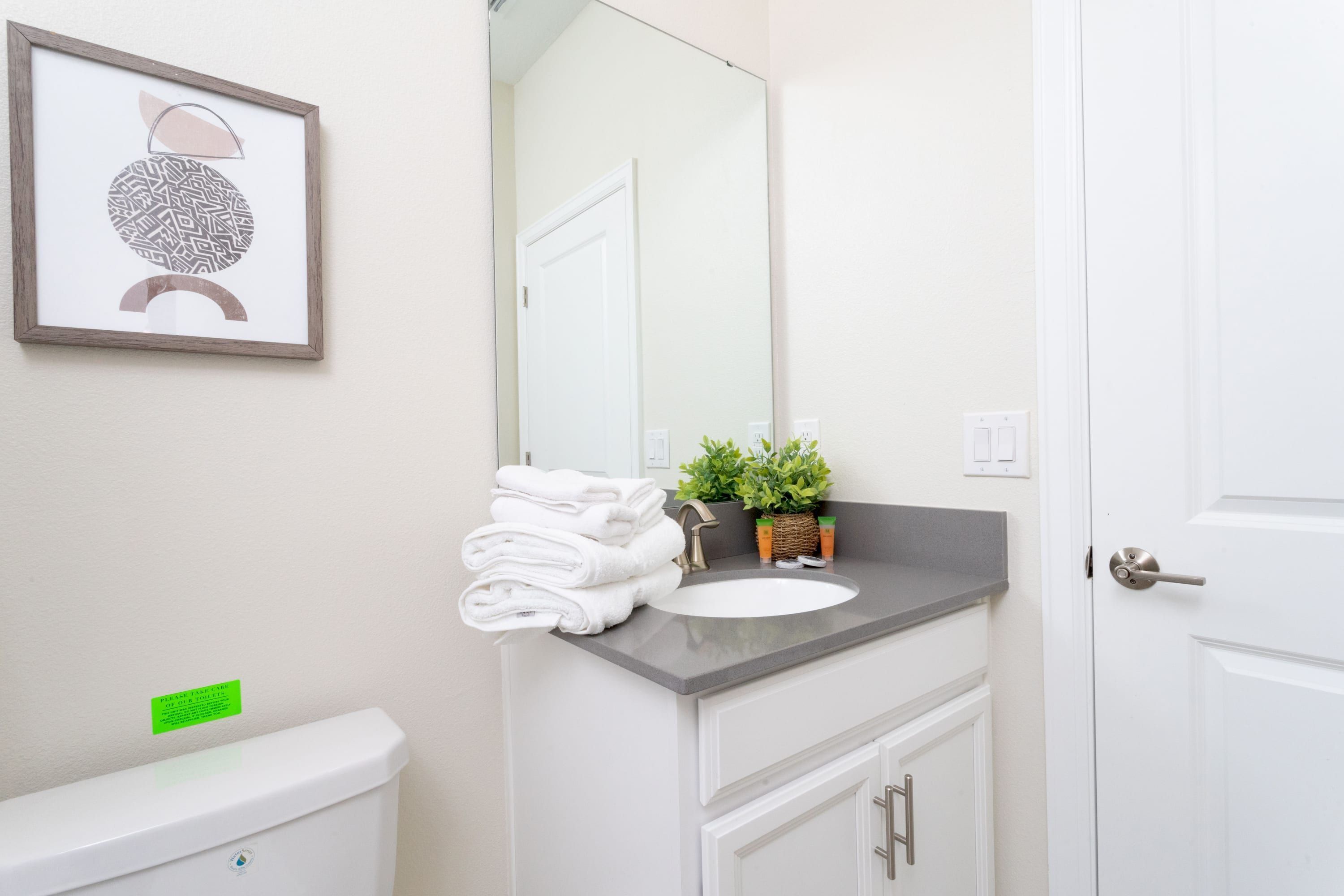 A bathroom with a toilet, sink, and a framed picture on the wall.
