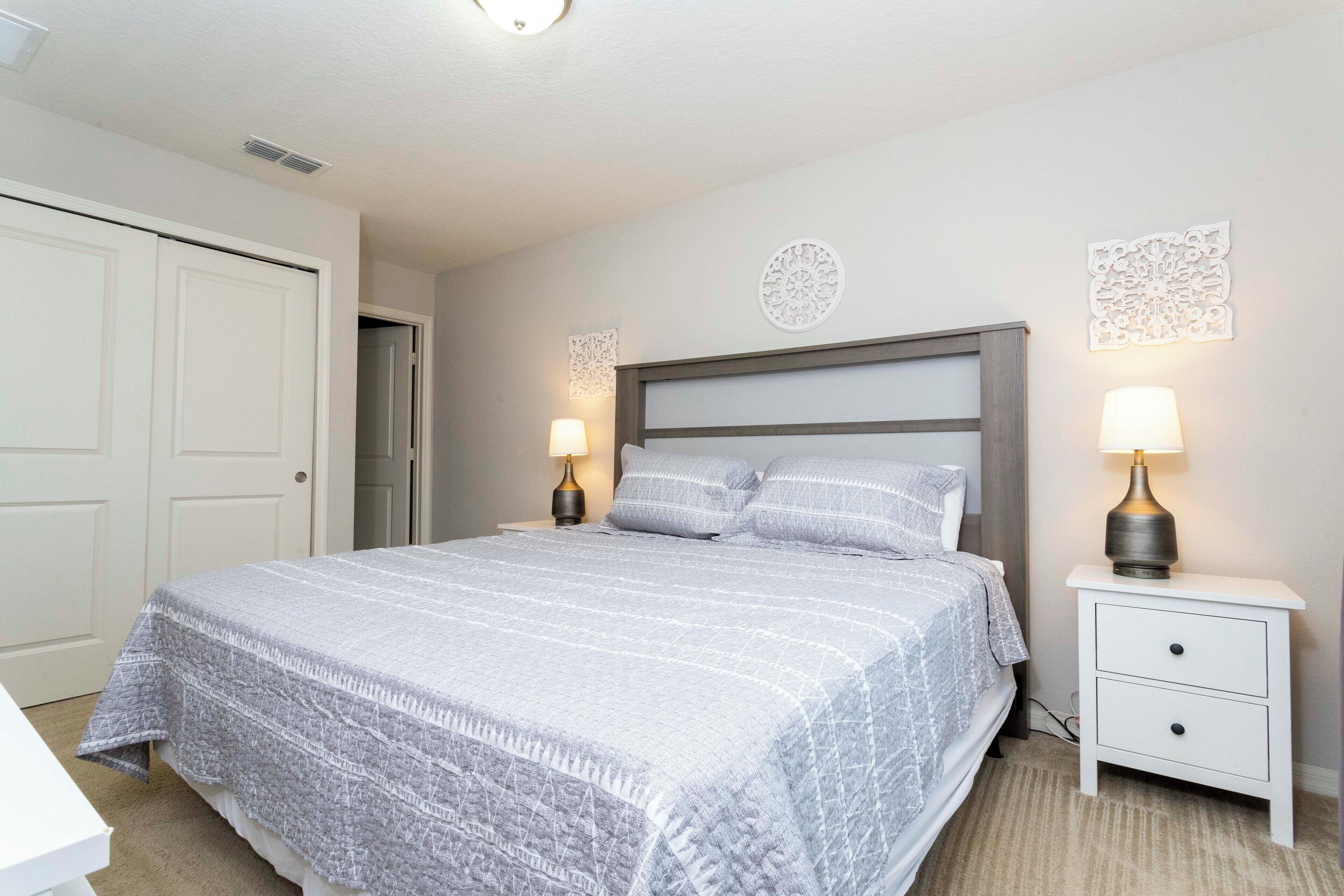 Une chambre à coucher comprenant un lit, deux tables de chevet avec des lampes, une porte et des éléments de décoration murale.