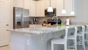 A modern kitchen with white cabinets, stainless steel appliances, and a marble countertop. - Four Bedrooms Townhome Close to Disney 5162a (Kissimmee)