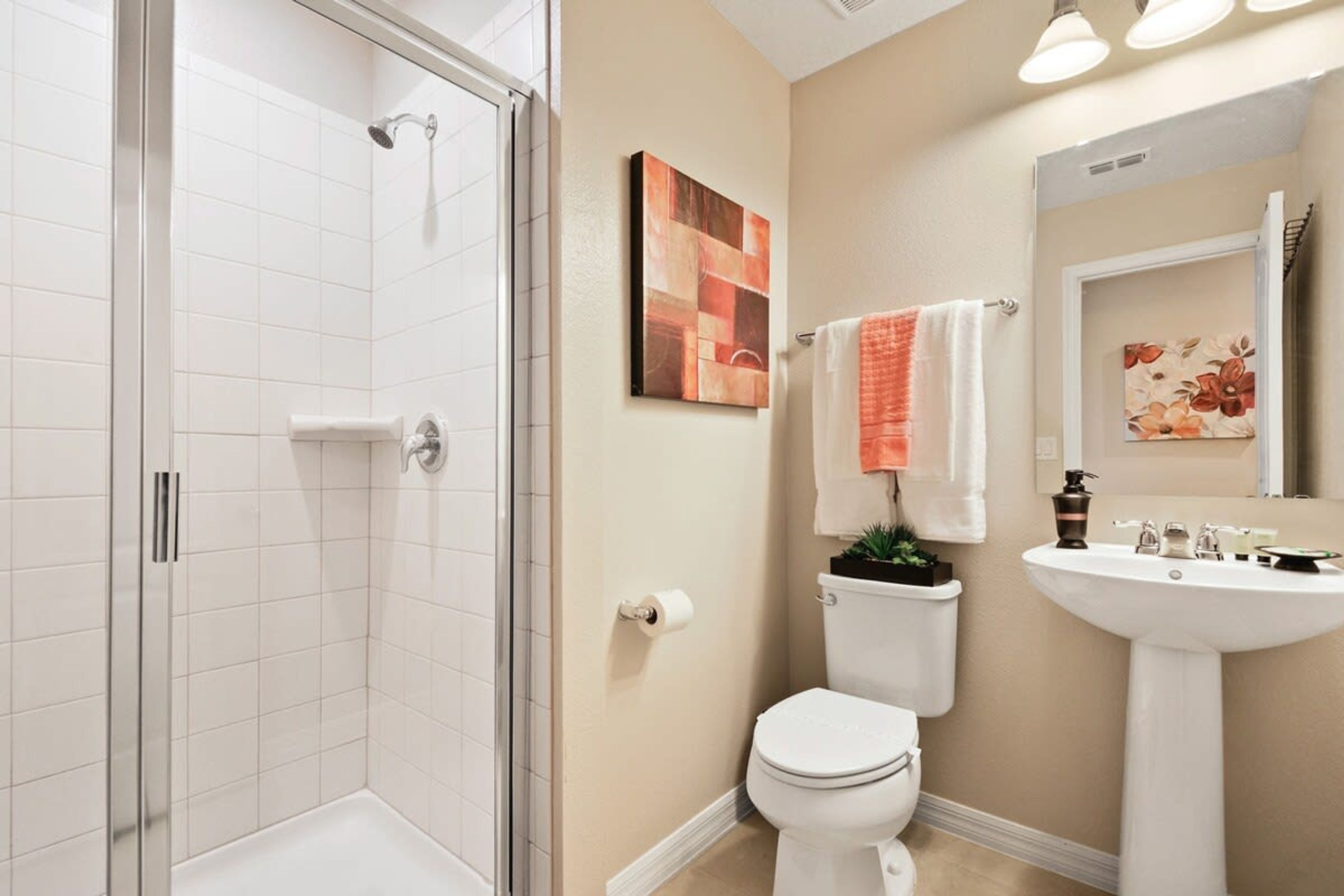 Un baño con ducha de vidrio, inodoro, lavabo y dos espejos fijos en la pared.