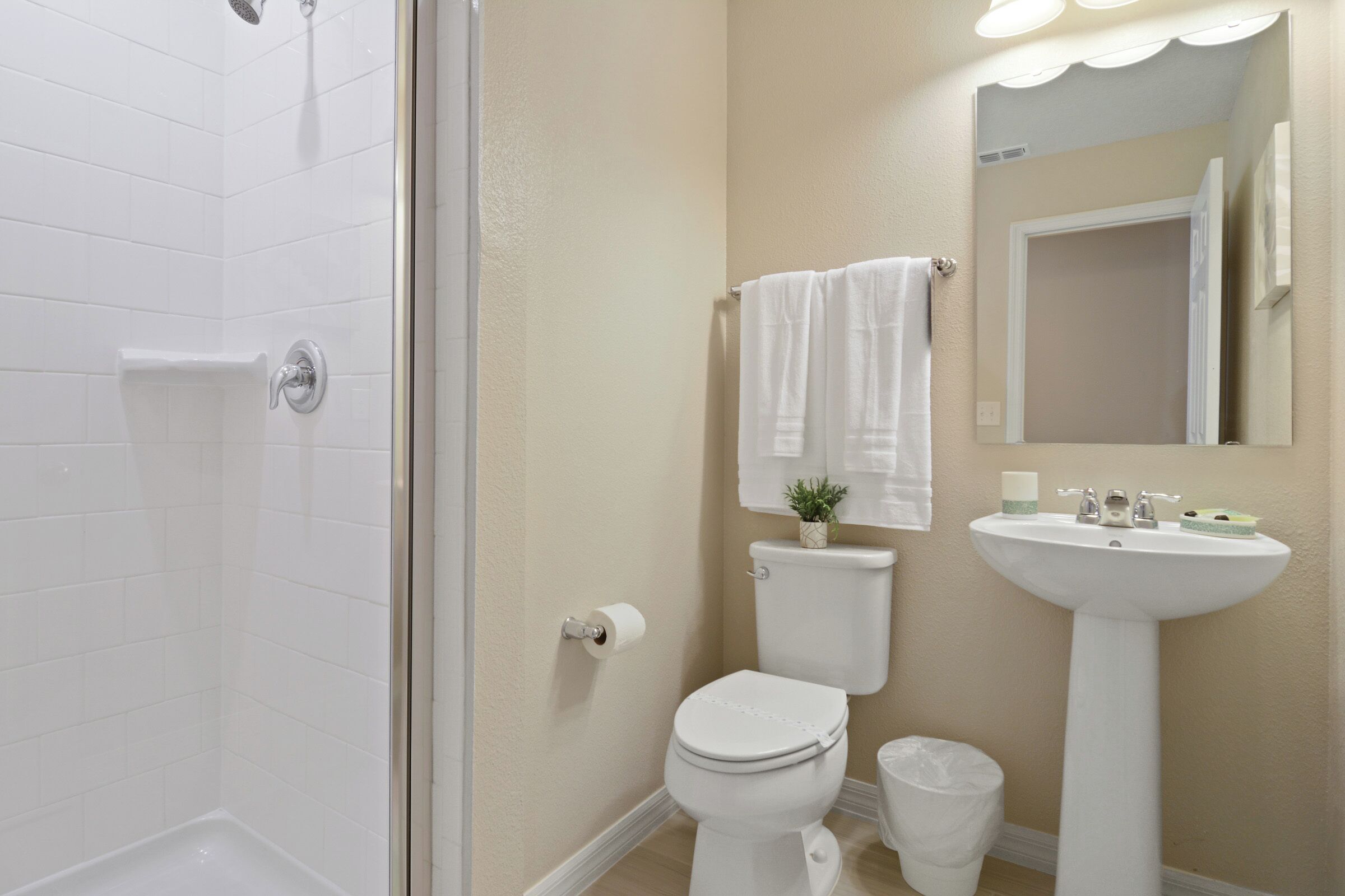 Un bagno con doccia, WC, lavandino e uno specchio.