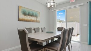 A dining area with a table and chairs, a painting on the wall, and an exit sign. - Wonderful 4 Bed Close to Disney w Gameroom 5150 (Kissimmee)