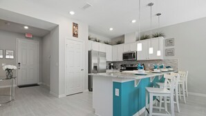 A modern kitchen with white cabinets, a central island with bar stools, stainless steel appliances, and pendant lighting. - Wonderful 4 Bed Close to Disney w Gameroom 5150 (Kissimmee)