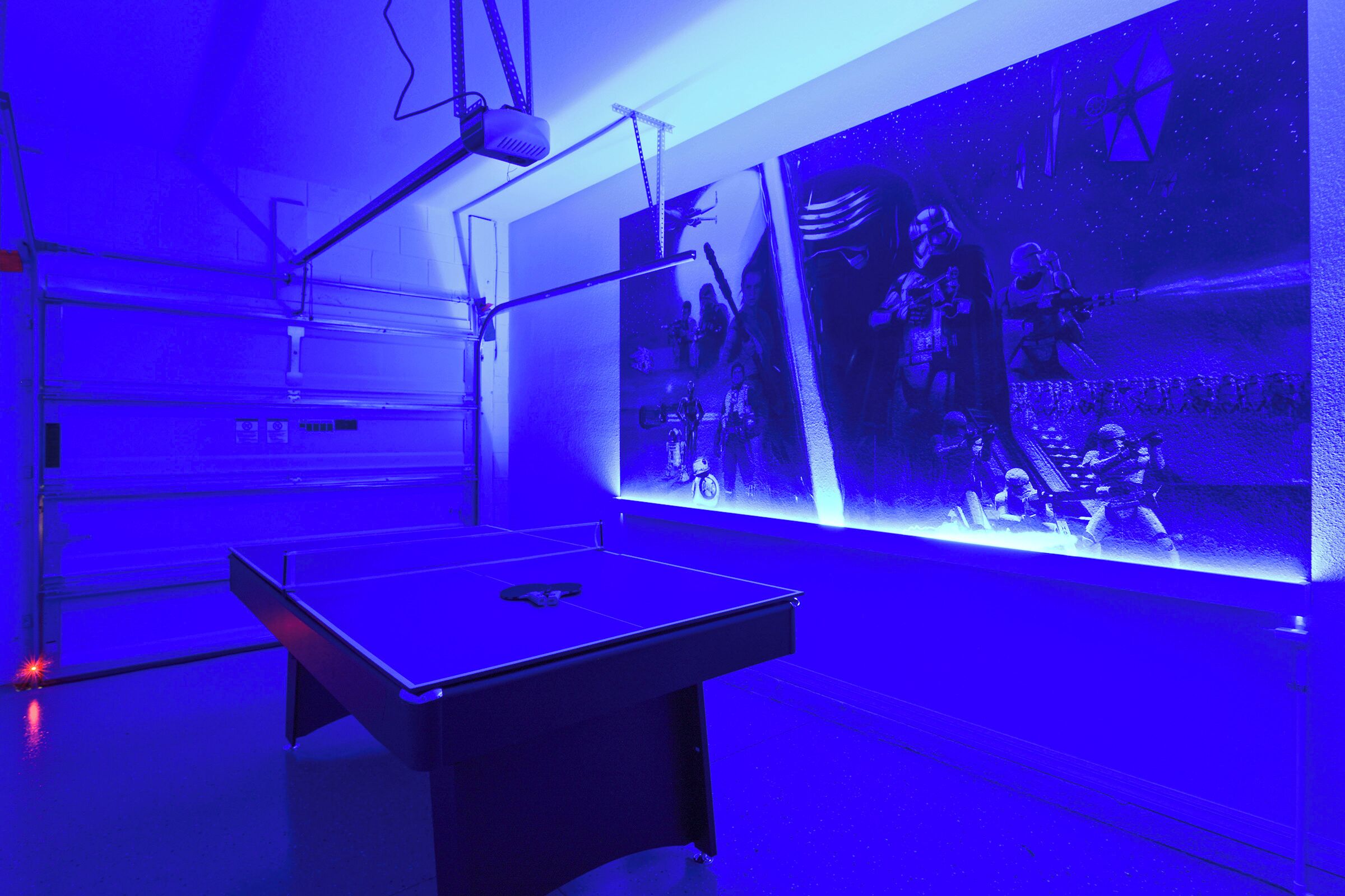 Une pièce équipée d’une table de billard, d’une grande fresque murale et d’un projecteur fixé au plafond.