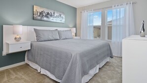 A bedroom with a bed, nightstands, a lamp, a cityscape painting, and a window with curtains. - Wonderful 4 Bed Close to Disney w Gameroom 5150 (Kissimmee)