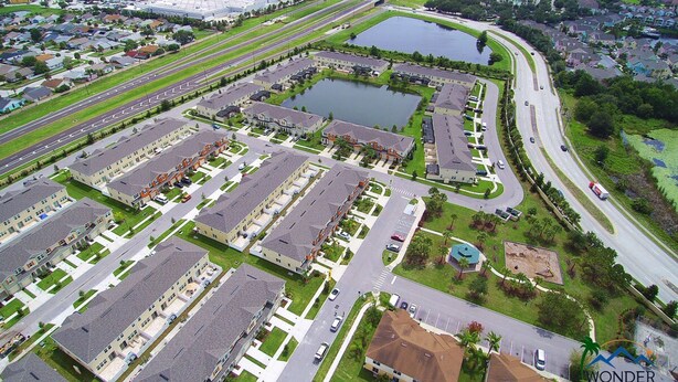 Une vue aérienne d’un quartier résidentiel comprenant de nombreux immeubles d’appartements, des routes et une vaste étendue d’eau.