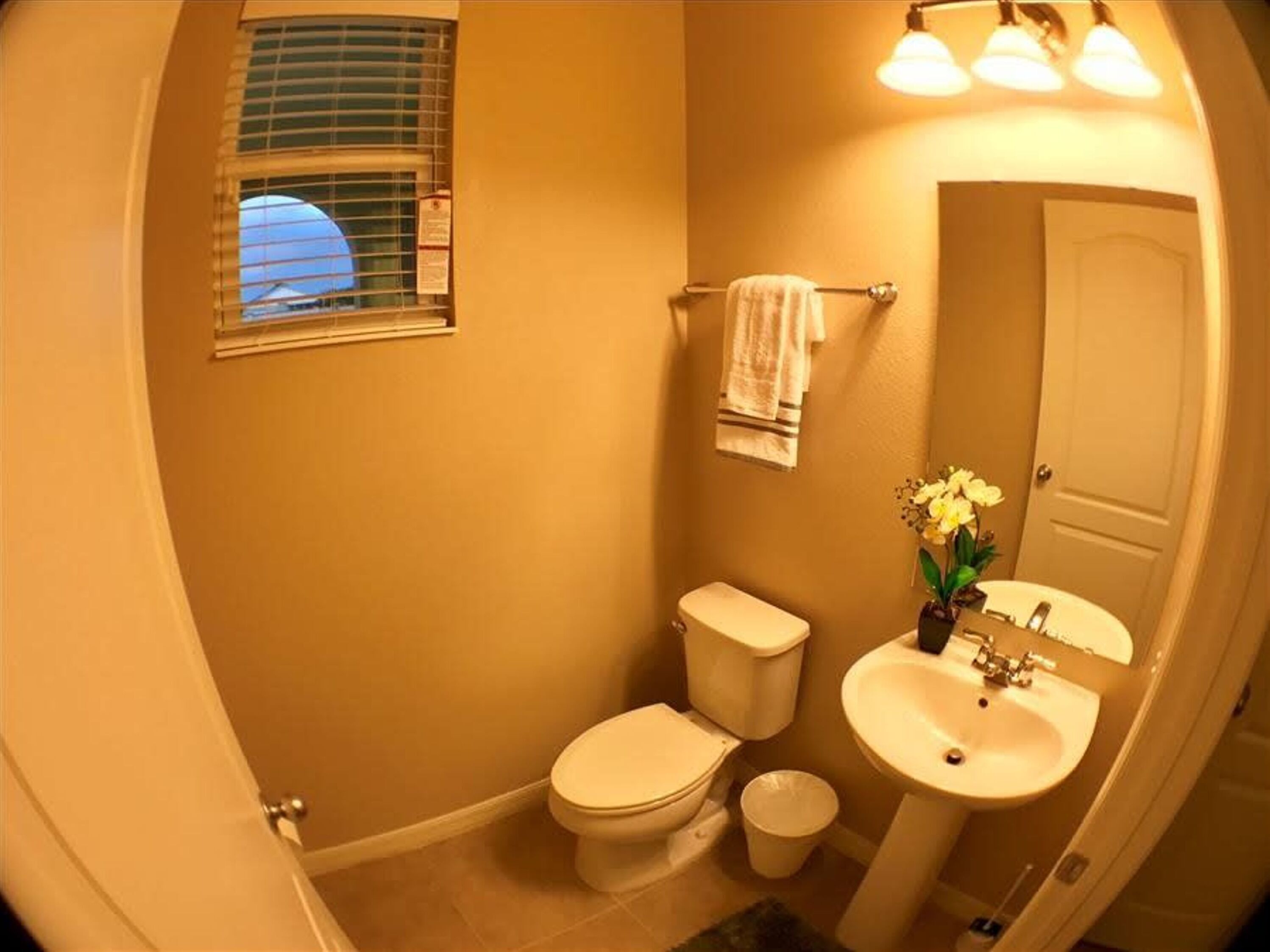 Ein Badezimmer mit Toilette, Waschbecken und einem Fenster mit Jalousien.