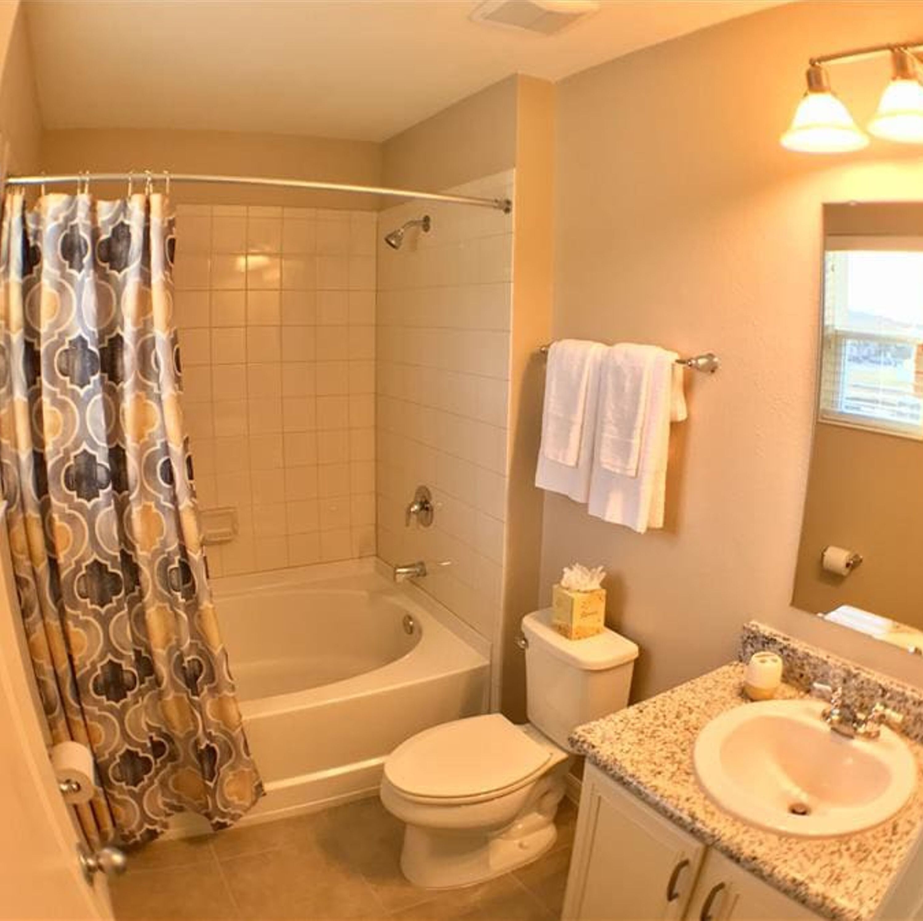 A bathroom with a shower, toilet, sink, and a towel rack with towels.