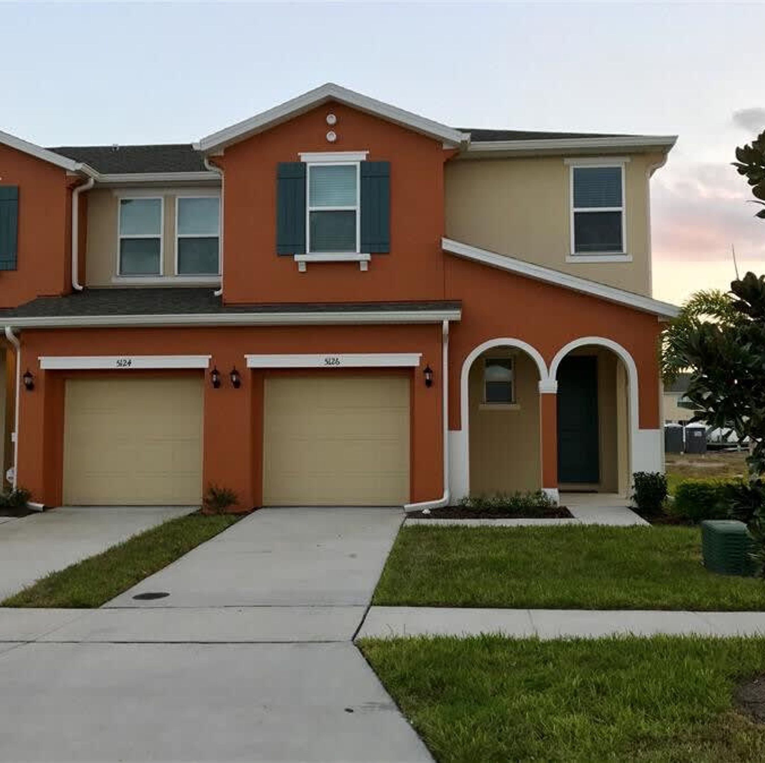 A two-story house with a garage, a front entrance with an archway, and a small front yard.