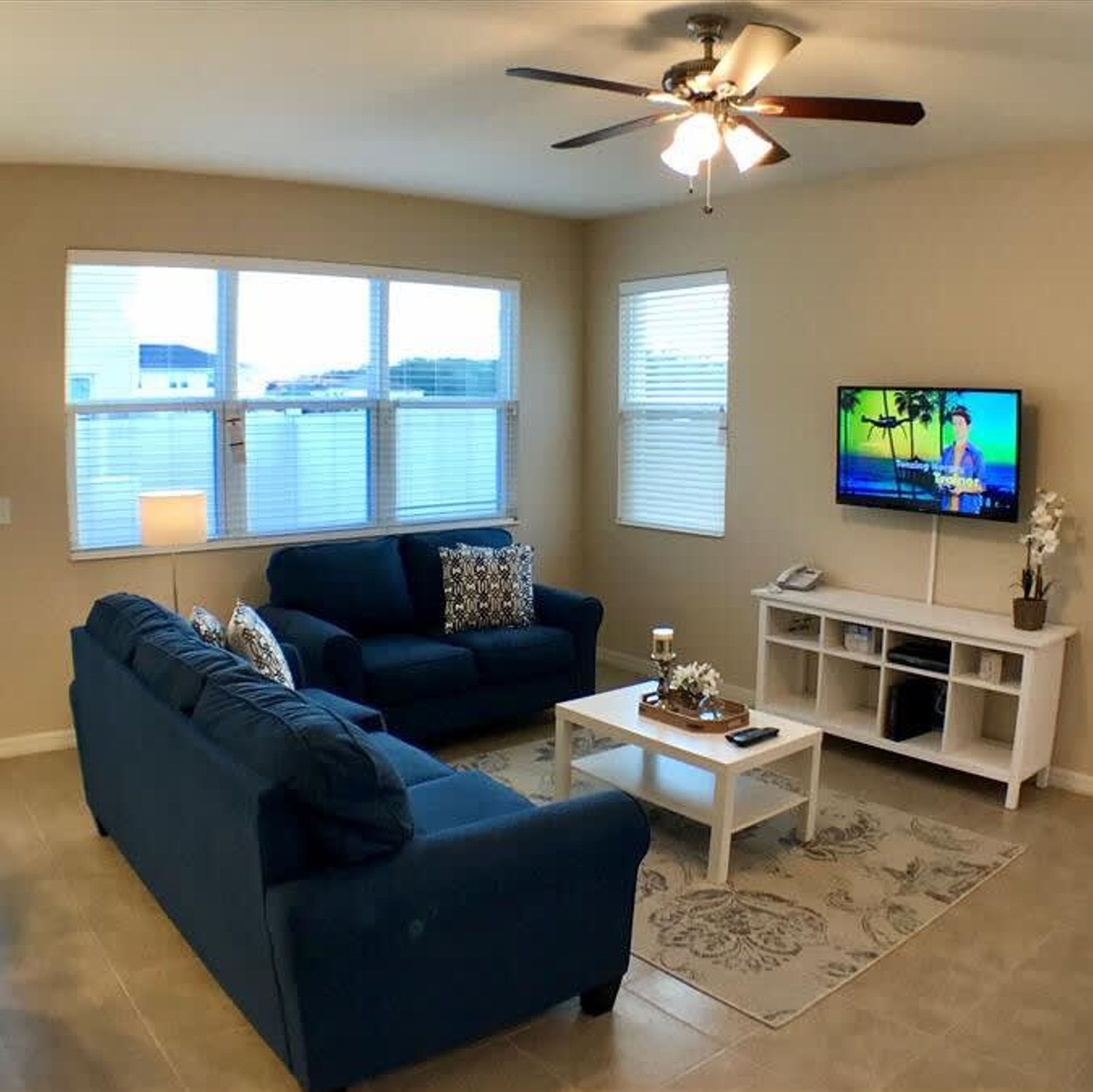 A living room with a blue sofa, a white coffee table, and a TV on a stand.