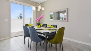 Een eetgedeelte met een tafel voor zes personen, zes stoelen, een kroonluchter, een grote spiegel en uitzicht op het buitengebied.