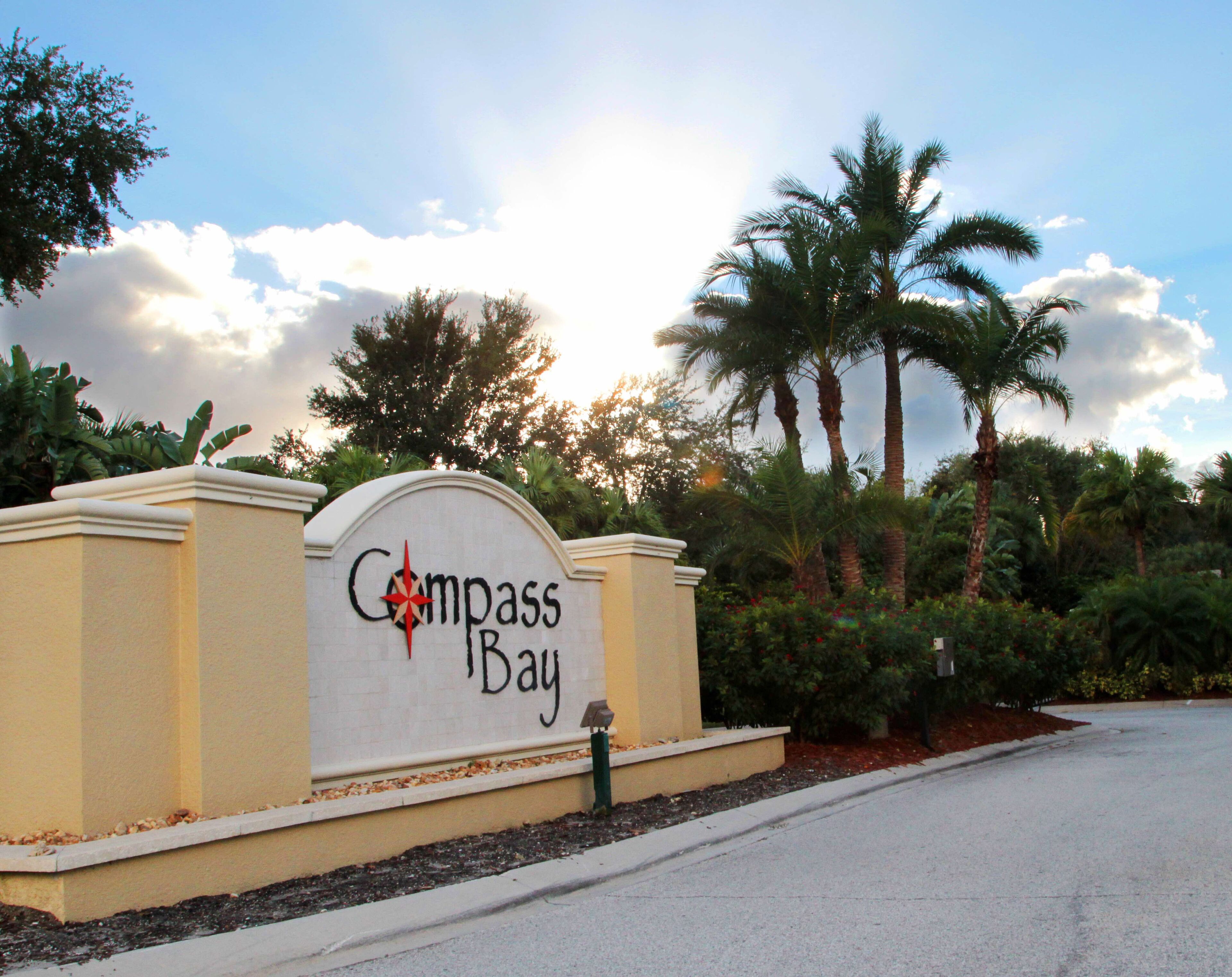 Une enseigne indiquant « Compass Bay », avec un palmier et un ciel dégagé en arrière-plan.