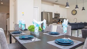 A modern dining area with a dark wooden table set for six, surrounded by grey upholstered chairs. - Family Friendly Four Bd w Pool at Storey Lake Resort 5035 (Kissimmee)
