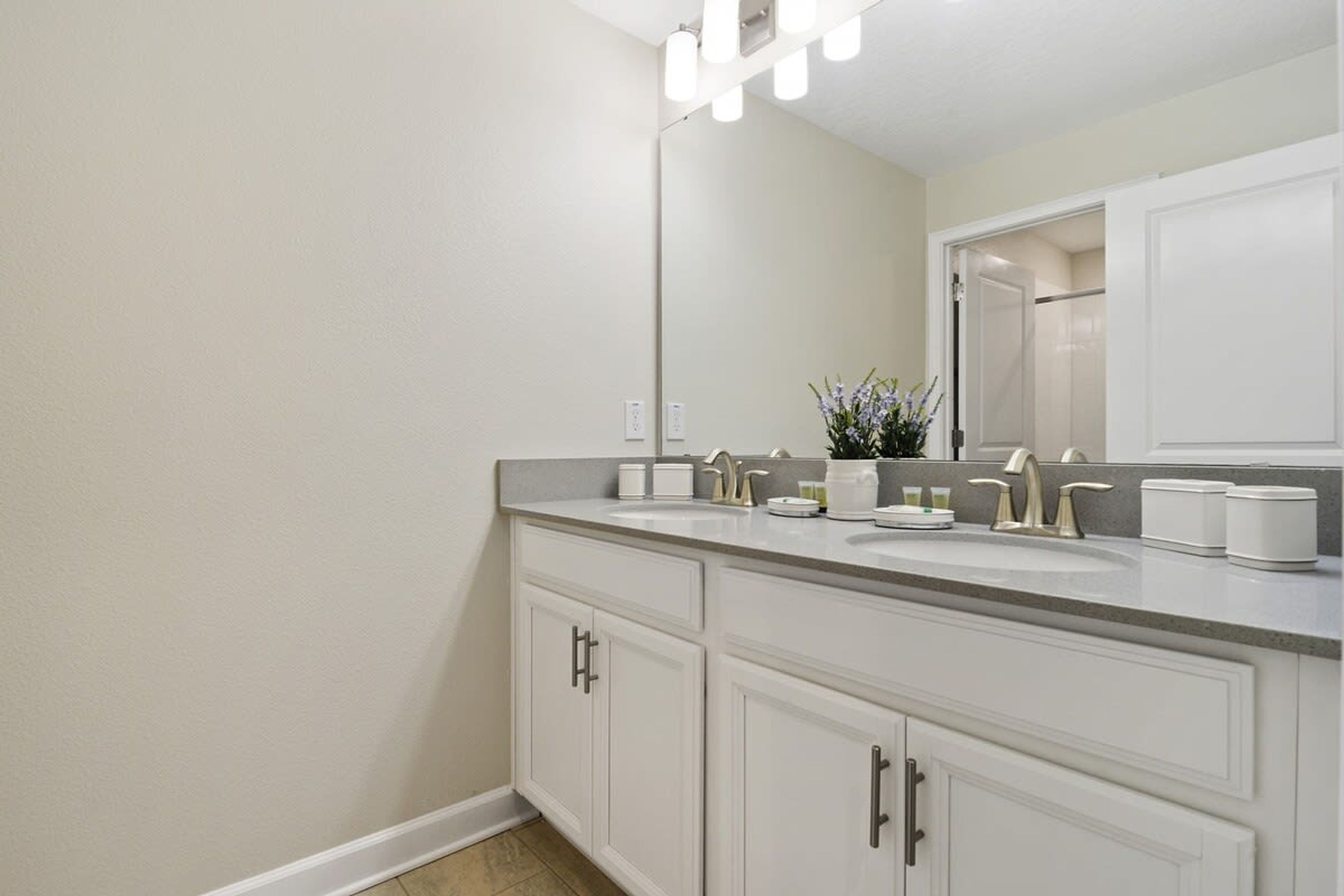 A modern bathroom with two sinks, a large mirror, and a vanity with cabinets.