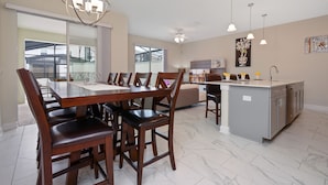 A spacious kitchen with a large island, modern pendant lights, and a view to the outside. - Four Bedroom Close to Disney w Pool 4898 (Kissimmee)