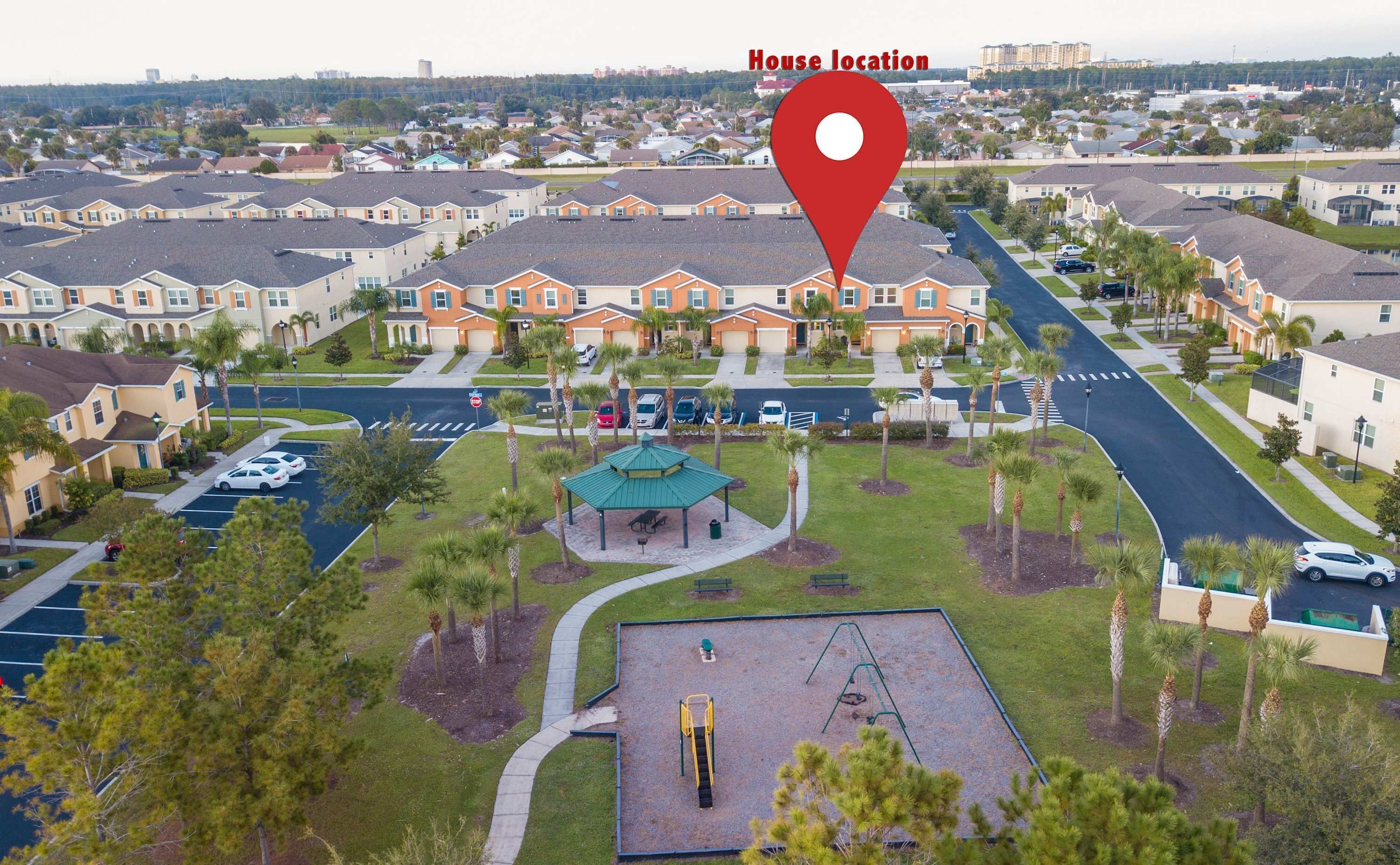 Un quartier résidentiel comprenant un parc, une aire de jeux et une rangée de maisons de ville.