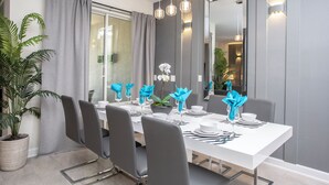 Un comedor moderno con una mesa blanca para seis personas, sillas grises y un espejo grande en la pared.
