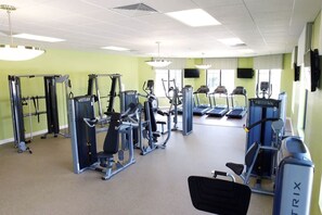 A gym with various exercise machines, a treadmill, and a television on the wall. - Sanitized Gorgeous Family Getaway 4Bd Home w Pool Close to Disney 4983 (Kissimmee)
