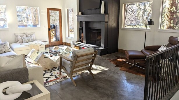 A modern living room with a fireplace, a sofa, a coffee table, and a dining area. - The Springs - Steps from Warm Springs Base (Ketchum)