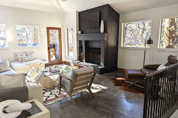 Bright light living area with wood burning fireplace and deck with hot tub.
