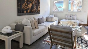 A modern living room with a large abstract painting, a sofa set, a coffee table, and a view of the outside through a skylight. - The Springs - Steps from Warm Springs Base (Ketchum)