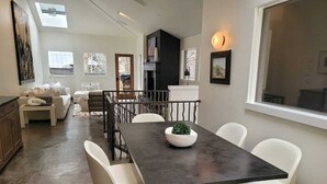 A modern dining area with a dark wooden table, white chairs, and a central plant. - The Springs - Steps from Warm Springs Base (Ketchum)