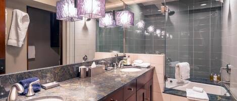 A modern bathroom with a large vanity, dual sinks, and a glass-enclosed shower.