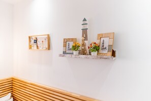 Una pared con dos marcos de madera, uno con un faro y otro con una escena de playa.