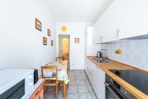 A compact kitchen with a microwave, stove, sink, and wooden countertop.