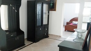 A room with a large black cabinet with glass doors, a smaller cabinet, and a bed with a red headboard. - Appartement HS à Bord de la mer Sousse Chott Meriam (Chott Meriam)