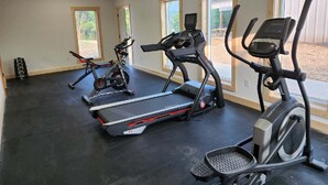 Ein Fitnessraum mit Laufbändern, Crosstrainern und einem stationären Fahrrad.