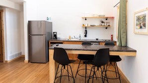 Een compacte keuken met een koelkast, een gootsteen en een bar met krukken.