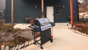 Een gebouw met een overdekte patio, een barbecue en een klein terras.